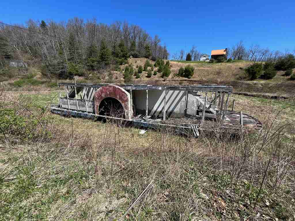 paddlewheel riverboat rotting in a field