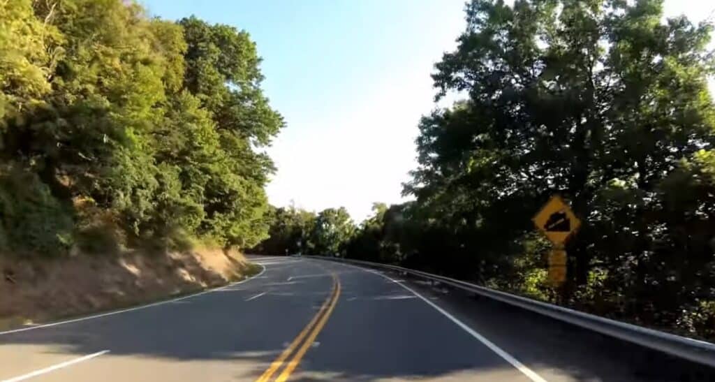 Modern Route 52 curve on Fancy Gap Mountain with steep-grade warning sign.