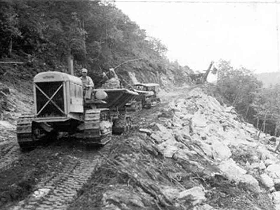 CCC workers building the Blue Ridge Parkway with bulldozers and trucks along a mountain slope