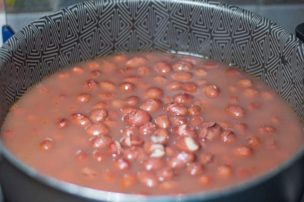 Pinto beans simmering in a pot of broth during long, slow cooking.