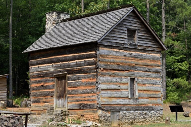 Preserved Appalachian log cabin with stone chimney and small window openings and Window Charms in Appalachian Cabins