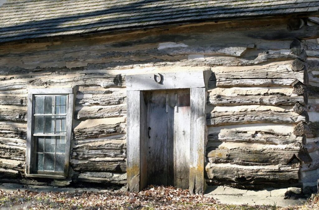 Historic log cabin doorway with a horseshoe mounted above the doorframe.