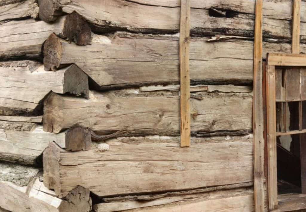 Corner joinery on a log cabin beside an Appalachian cabin chimney that shows the builder’s level of skill.