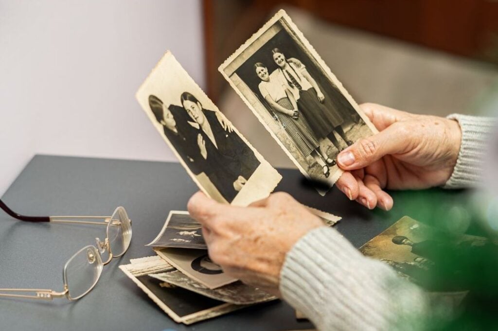 Hands holding old family photographs, a reminder of how Appalachian family stories are passed down through memory