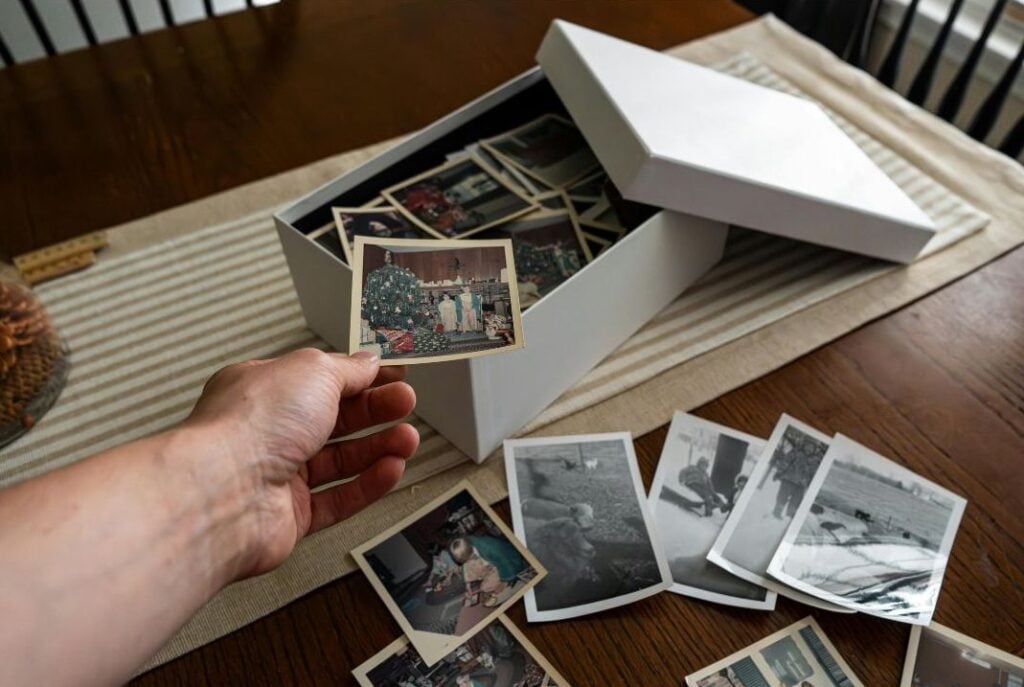 Box of old family photographs spread across a table, part of many Appalachian family stories that survive without written labels