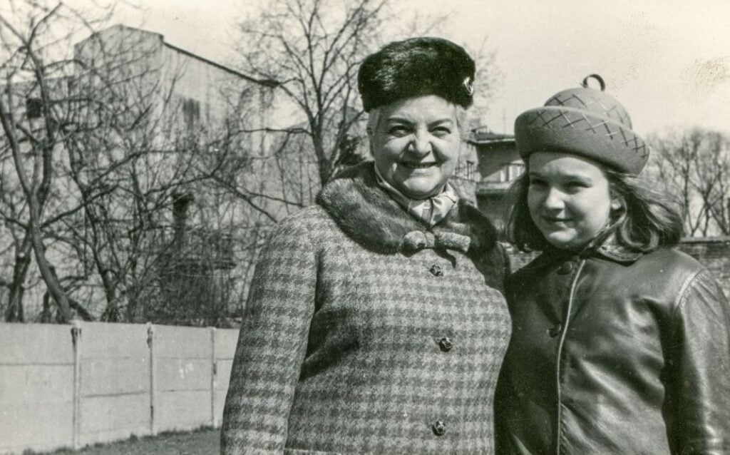 Older woman standing beside a young girl in a mid-20th century family photograph