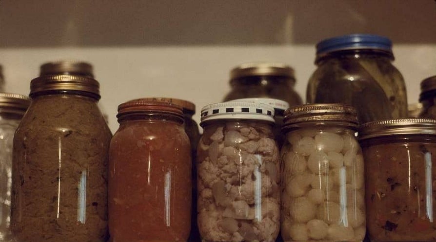 Shelf of home-canned foods, including meat jars associated with canning sausage and other preserved foods.