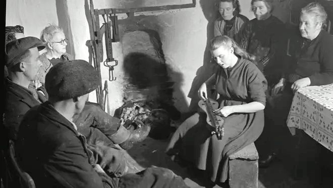Appalachian musician playing dulcimer in a small indoor gathering with listeners seated nearby