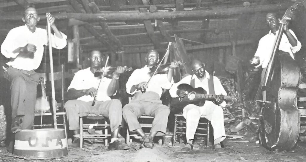 Early Appalachian string band with fiddle, guitar, and bass performing together in a rustic setting