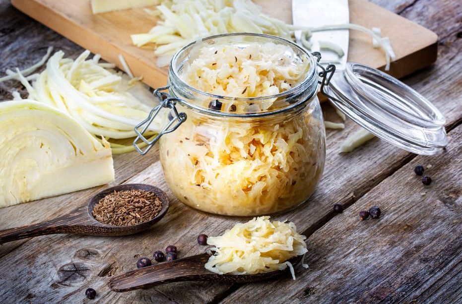 Jar of homemade sauerkraut with sliced cabbage on a wooden table