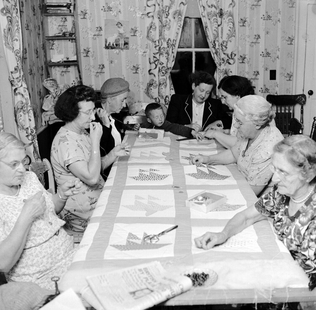 Quilting bee showing women gathered around a table during an Appalachian work gathering