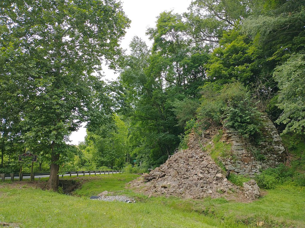 Collapsed iron furnace ruins with stone debris and partial structure remaining