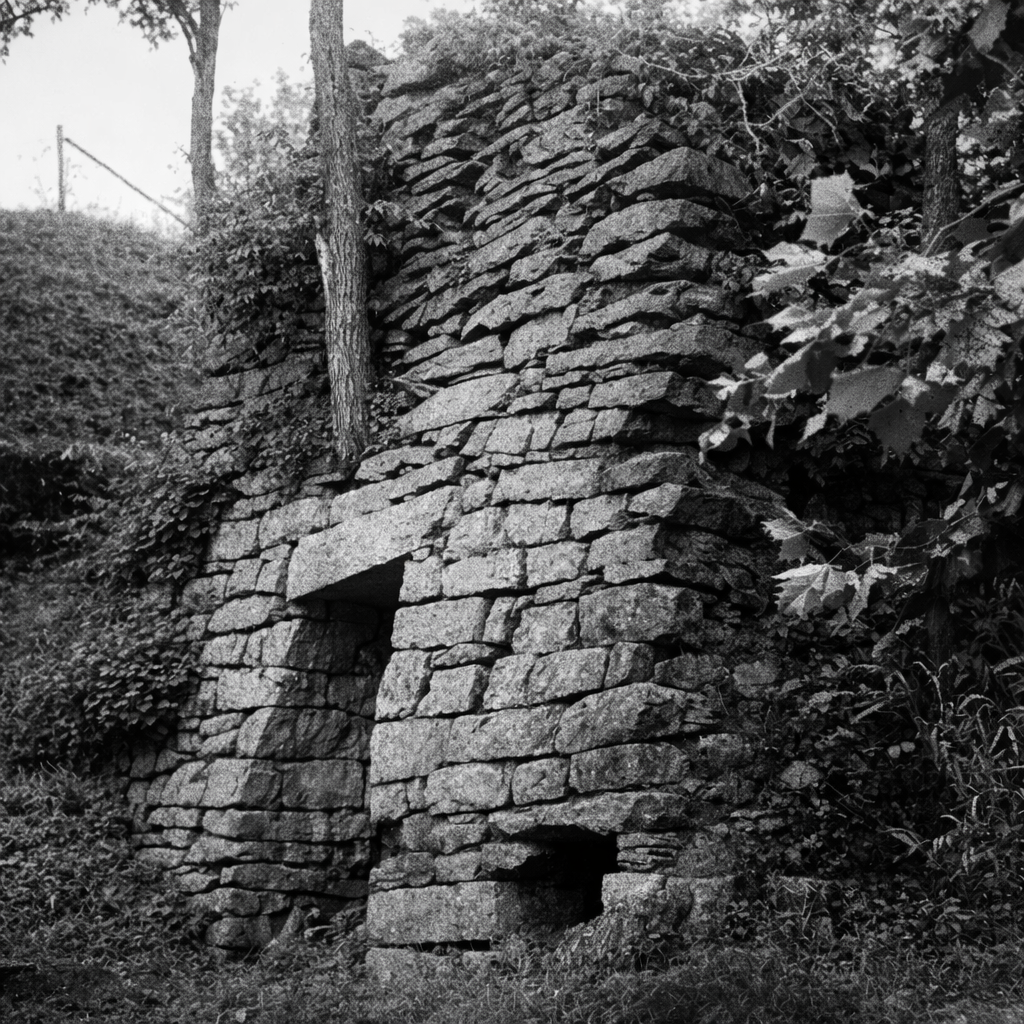 Historic iron furnace ruin with partial stone wall and visible opening