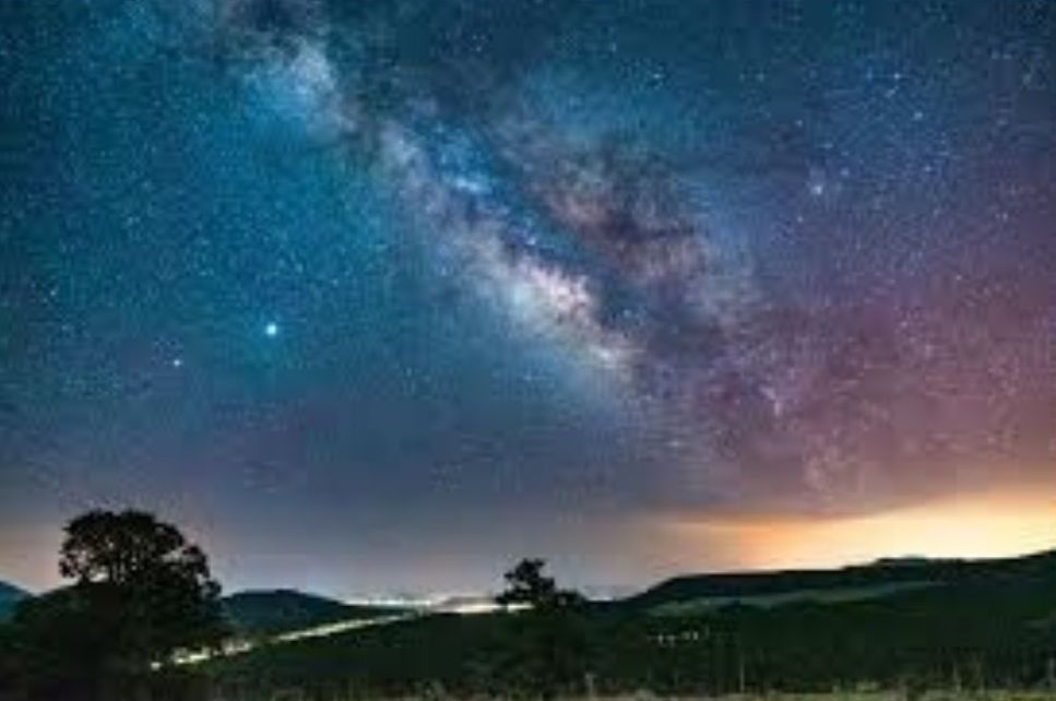 Blue Ridge night sky above mountain ridges with distant town glow on the horizon