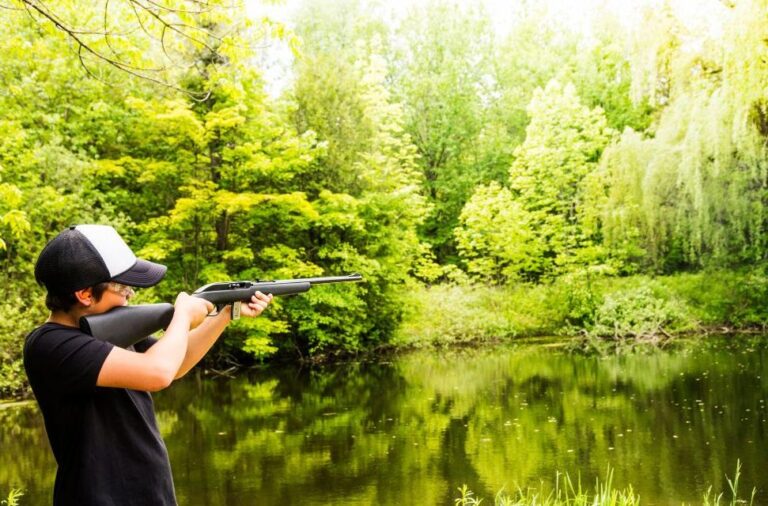 Young hunter carrying a rifle near a creek in Appalachia
