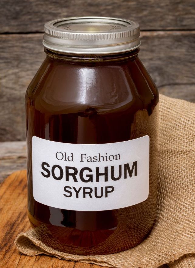 Jar labeled sorghum syrup displayed on a rustic wooden surface