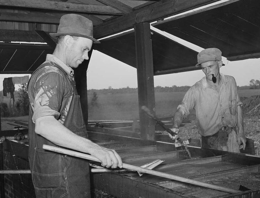Workers boiling sorghum juice into sorghum syrup at a community mill