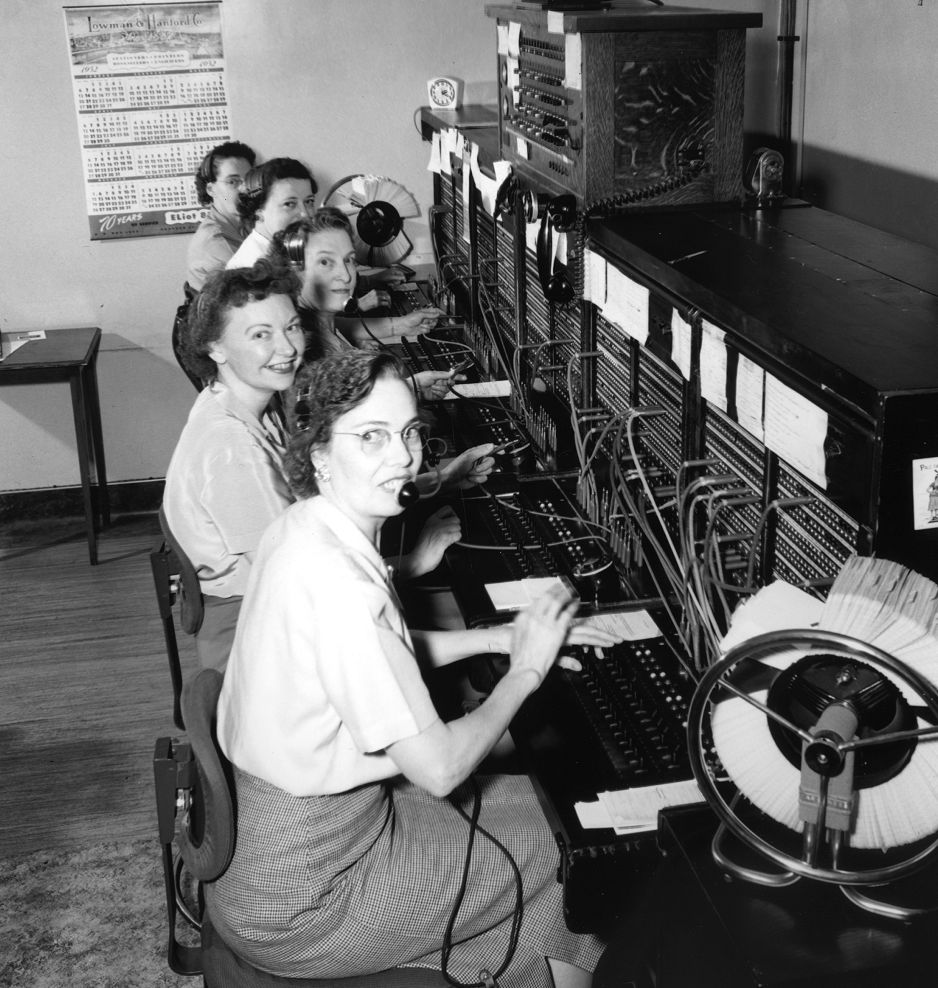 Telephone operators working together at a manual switchboard in the early 1950s.