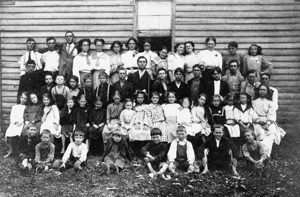 Students and teacher gathered outside a rural schoolhouse in the early twentieth century.