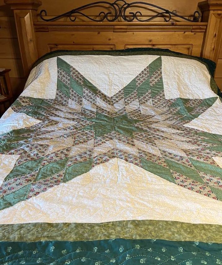 Green and cream star quilt displayed on a wooden bed in Galax, Virginia.